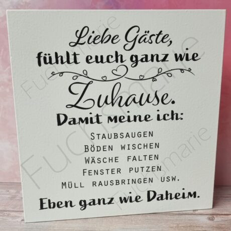 Holzschild mit Text: Liebe Gäste fühlt euch wie Zuhause. Damit meine ich: Staubsaugen, Böden wischen, Wäsche falten, Fenster putzen. Eben ganz wie Daheim.